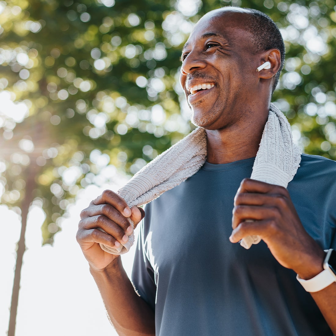 Man smiling outdoors in the sun after a workout.
